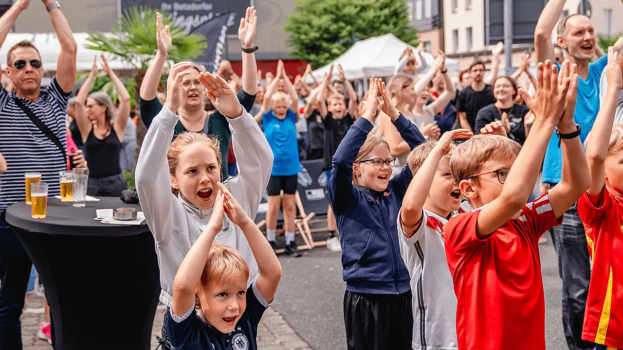 Kinder und Erwachsene machen halten die Hände in die Luft und tanzen bei einer Veranstaltung.