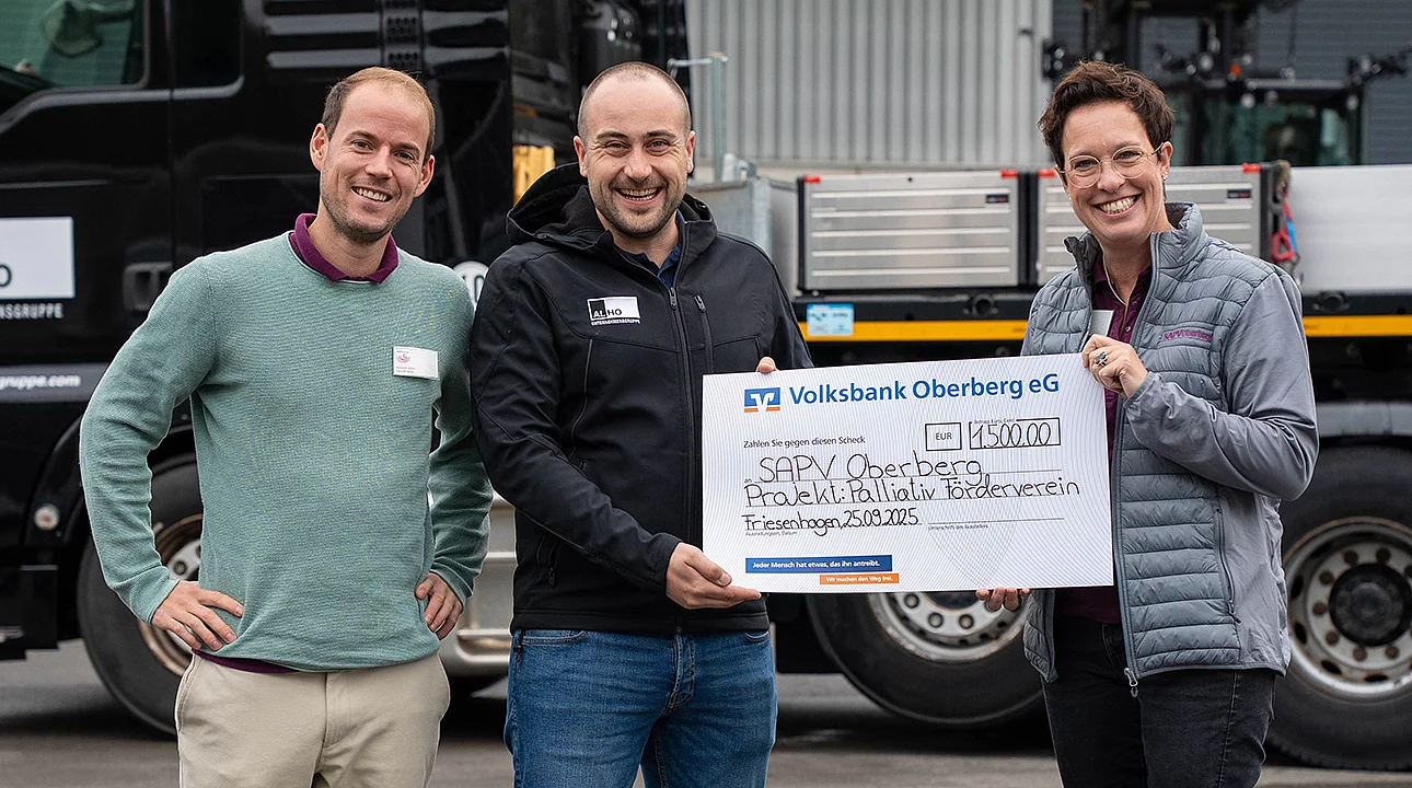 Drei Personen halten einen großen Scheck von 1.500 Euro. Er ist von der Volksbank Oberberg eG an SAPV Oberberg, Projekt Palliativ Förderverein, datiert auf 25.09.2023. Im Hintergrund befindet sich ein schwarzes Fahrzeug.