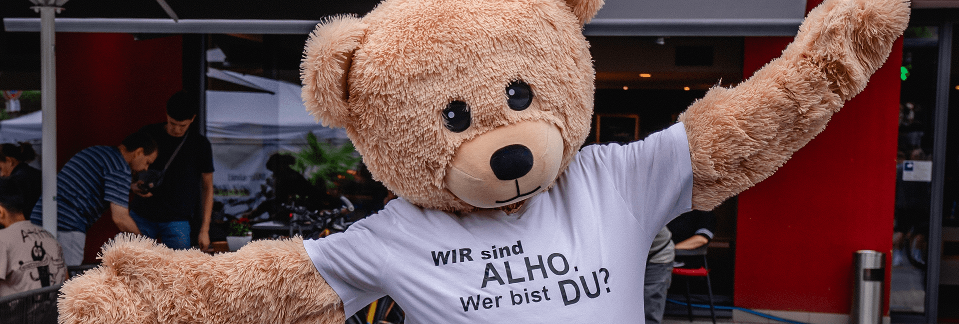 ALHO-Maskottchen mit ausgebreiteten Armen 