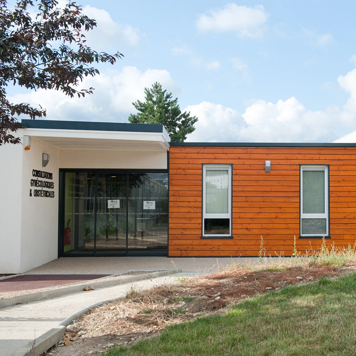 Extension modulaire d'un bâtiment de santé avec bardage bois et accès vitré.